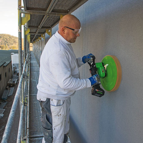 Plasterer using 12 inch cordless power sponge float on exterior wall
